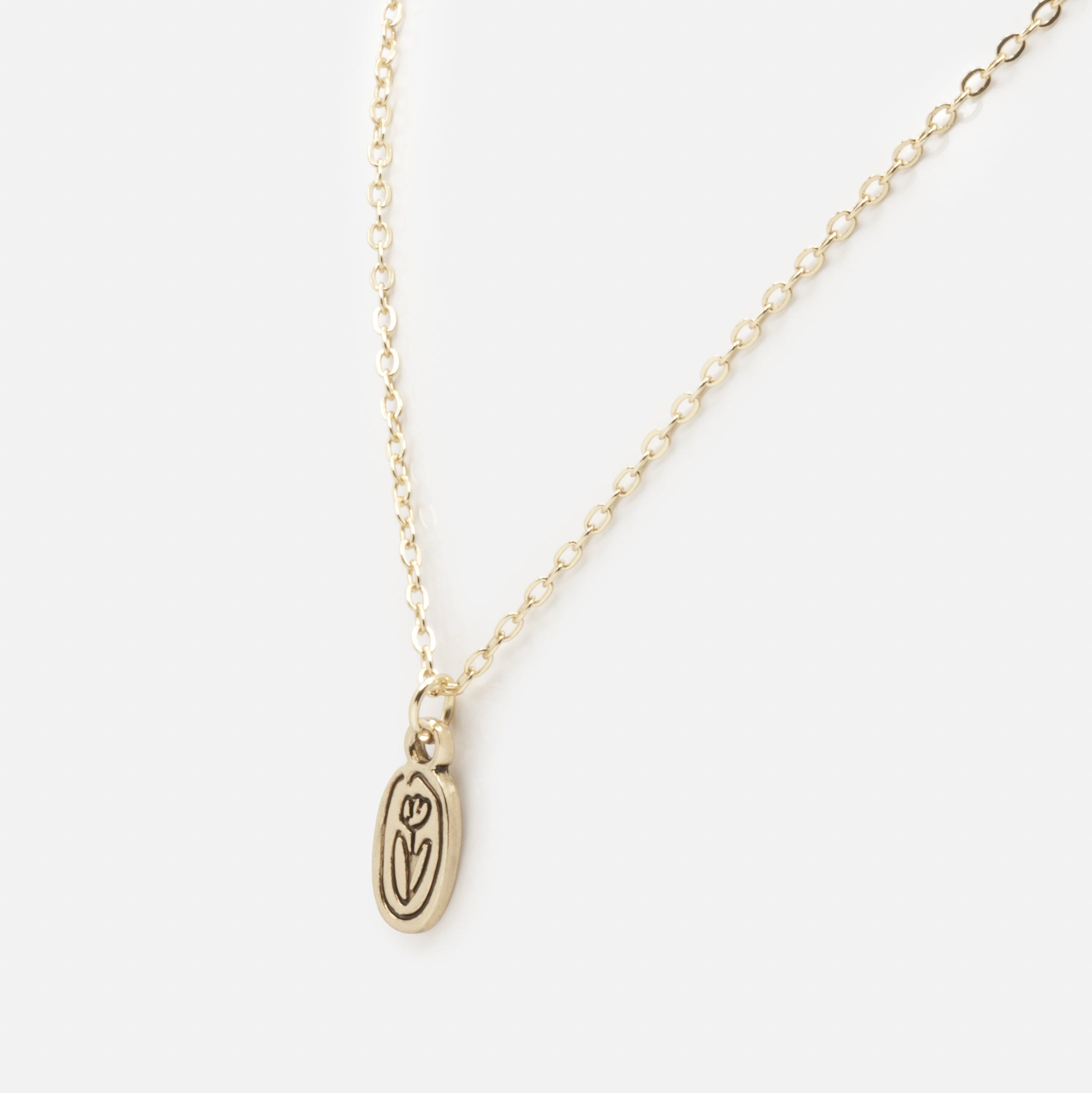 Gold necklace with black engraved flower charm