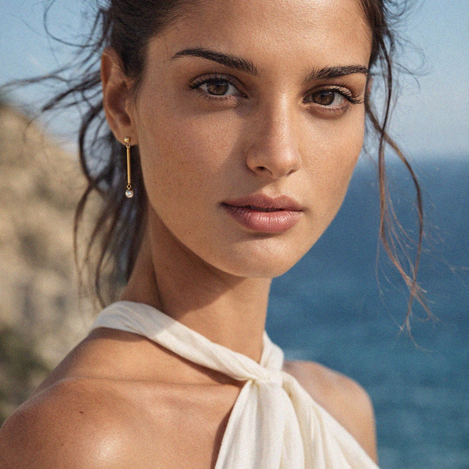 Bizou SF253E004GL – Woman wearing gold bar pearl drop earrings by the sea, Mediterranean lifestyle, Bizou jewelry