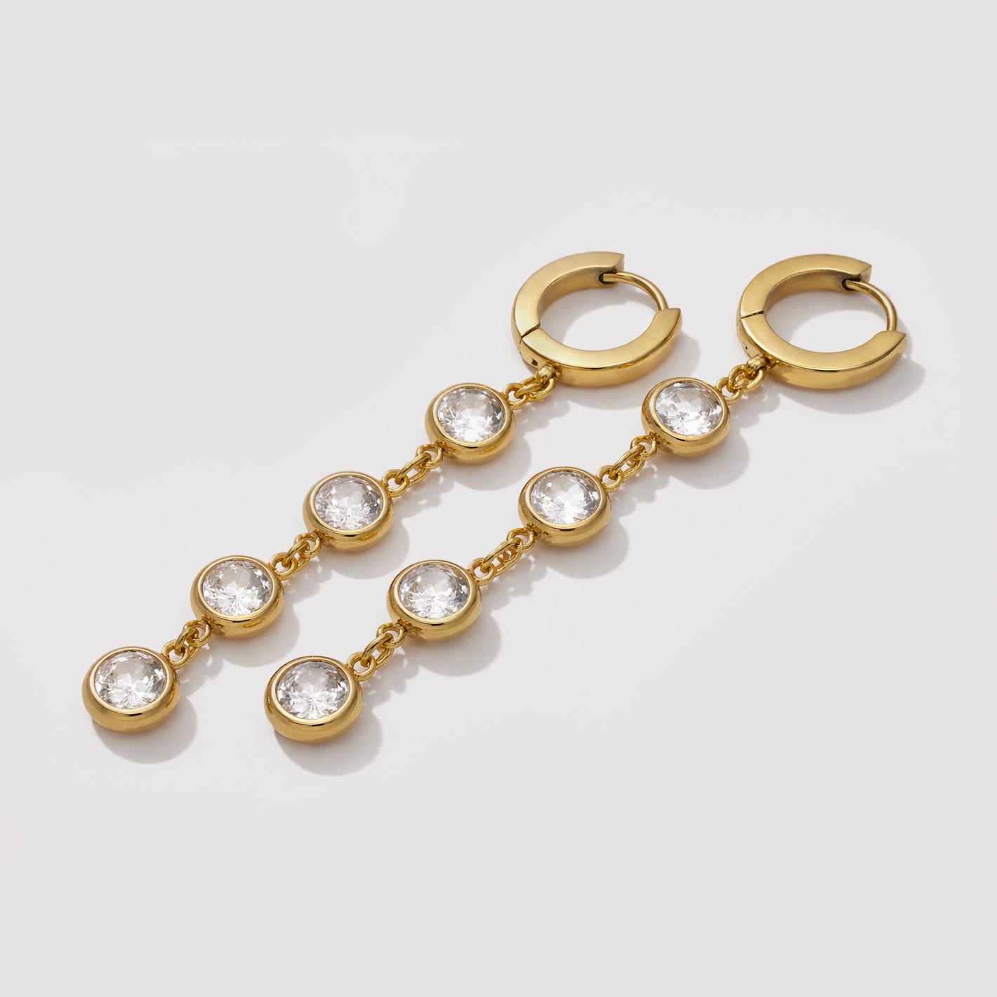 Bizou SF253E005GL – Gold stainless steel huggie earrings with cascading cubic zirconia pendant chain, angled view, Bizou jewelry