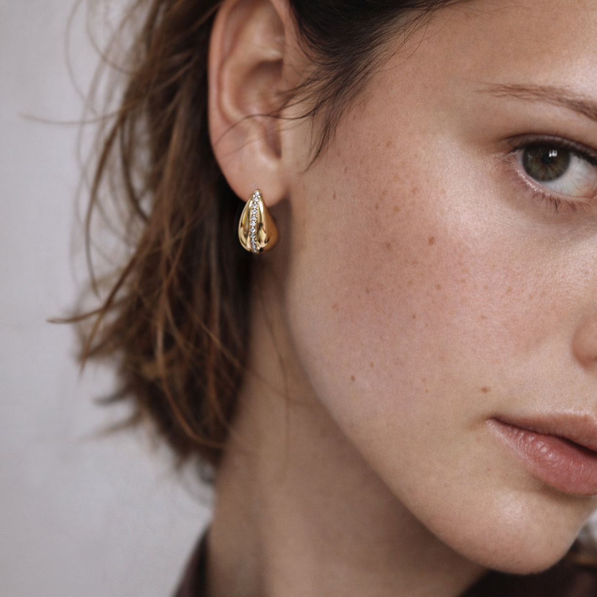 Bizou SF253E007GL – Woman wearing gold chunky teardrop pavé cubic zirconia stainless steel earrings, close-up, Bizou jewelry