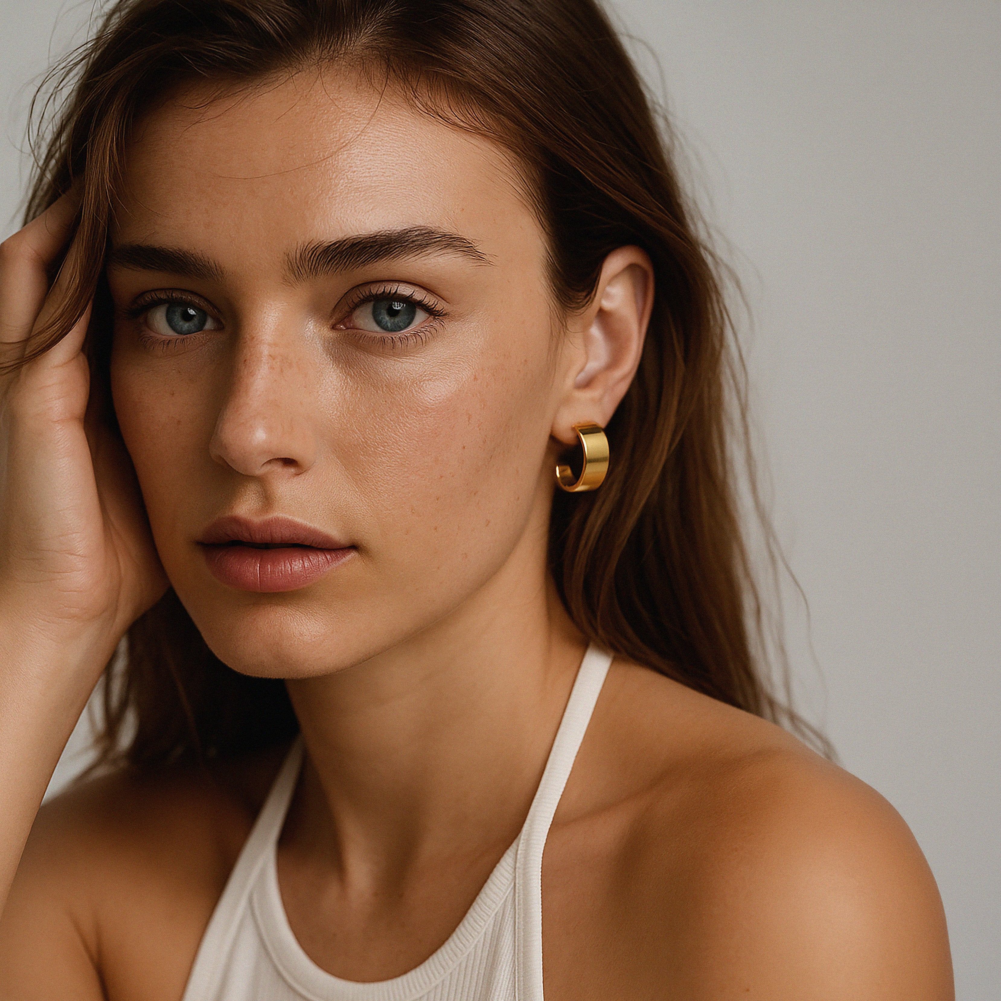Bizou SF253E008GL – Woman wearing gold wide band hoop earrings in stainless steel, close-up side profile, Bizou jewelry