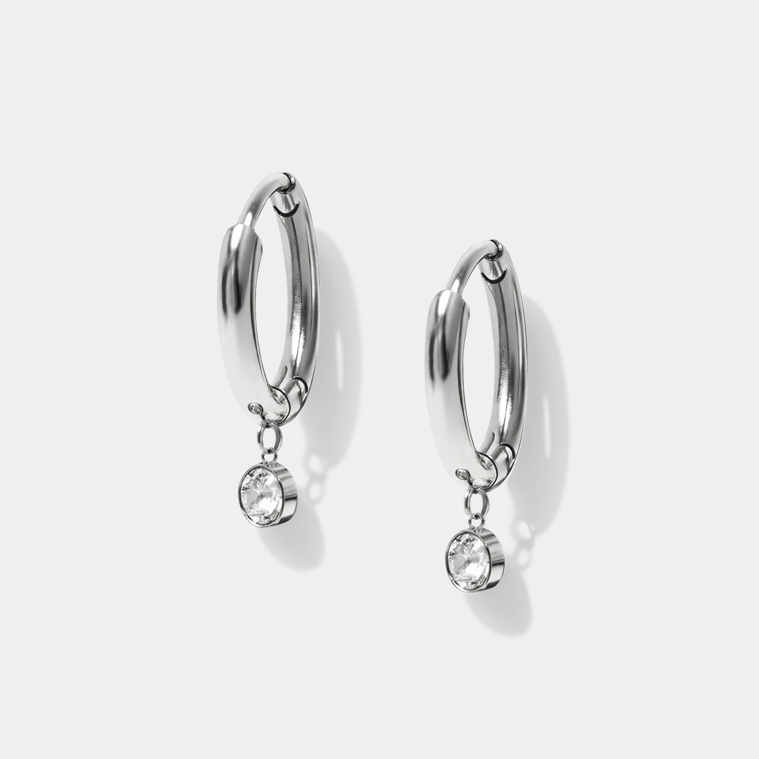 Bizou SS201GE06AR – Silver huggie hoop earrings with bezel-set cubic zirconia drop charm in stainless steel, angled view, Bizou jewelry