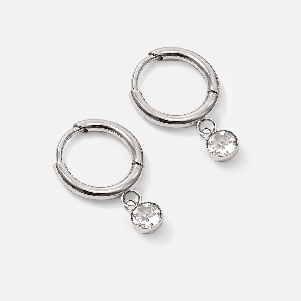 Bizou SS201GE06AR – Silver stainless steel huggie hoop earrings with dangling cubic zirconia charm, click closure, front view, Bizou jewelry