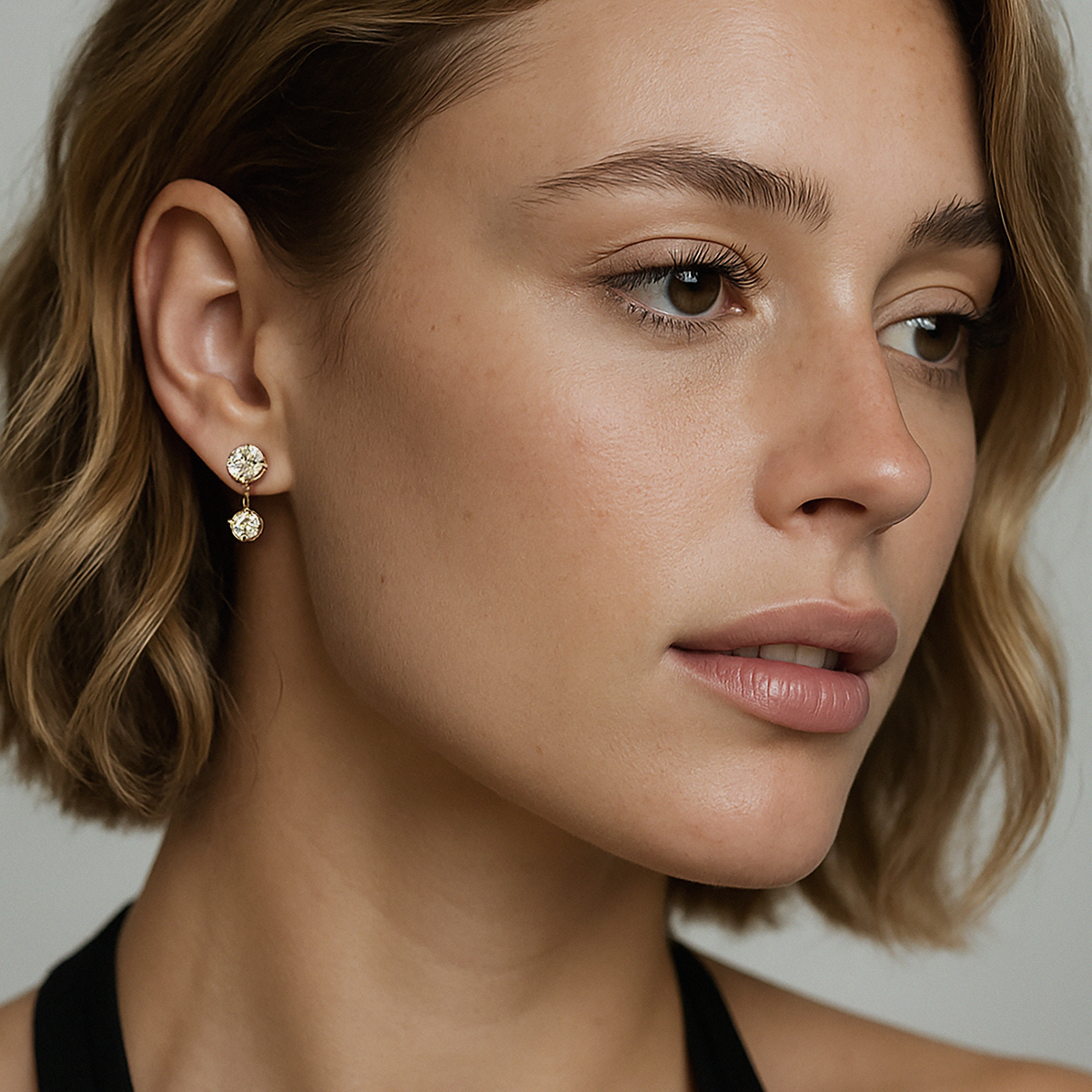 Bizou SS253E011GL – Woman wearing gold double CZ drop earrings in stainless steel, elegant dangle, side profile, Bizou jewelry