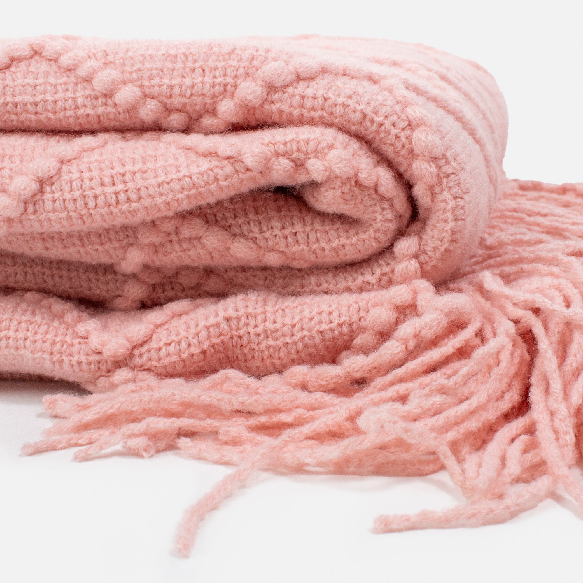 Pale pink blanket with diamond patterns and fringes
