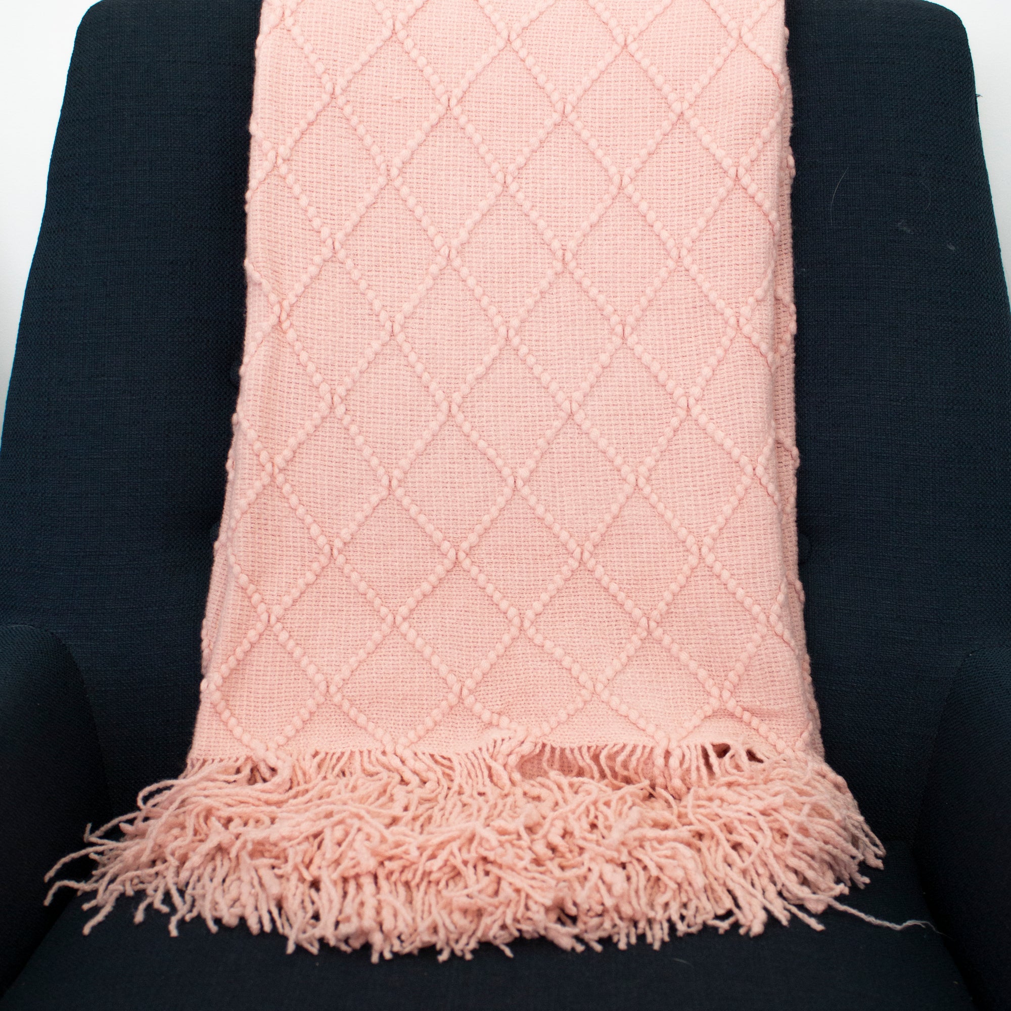 Pale pink blanket with diamond patterns and fringes