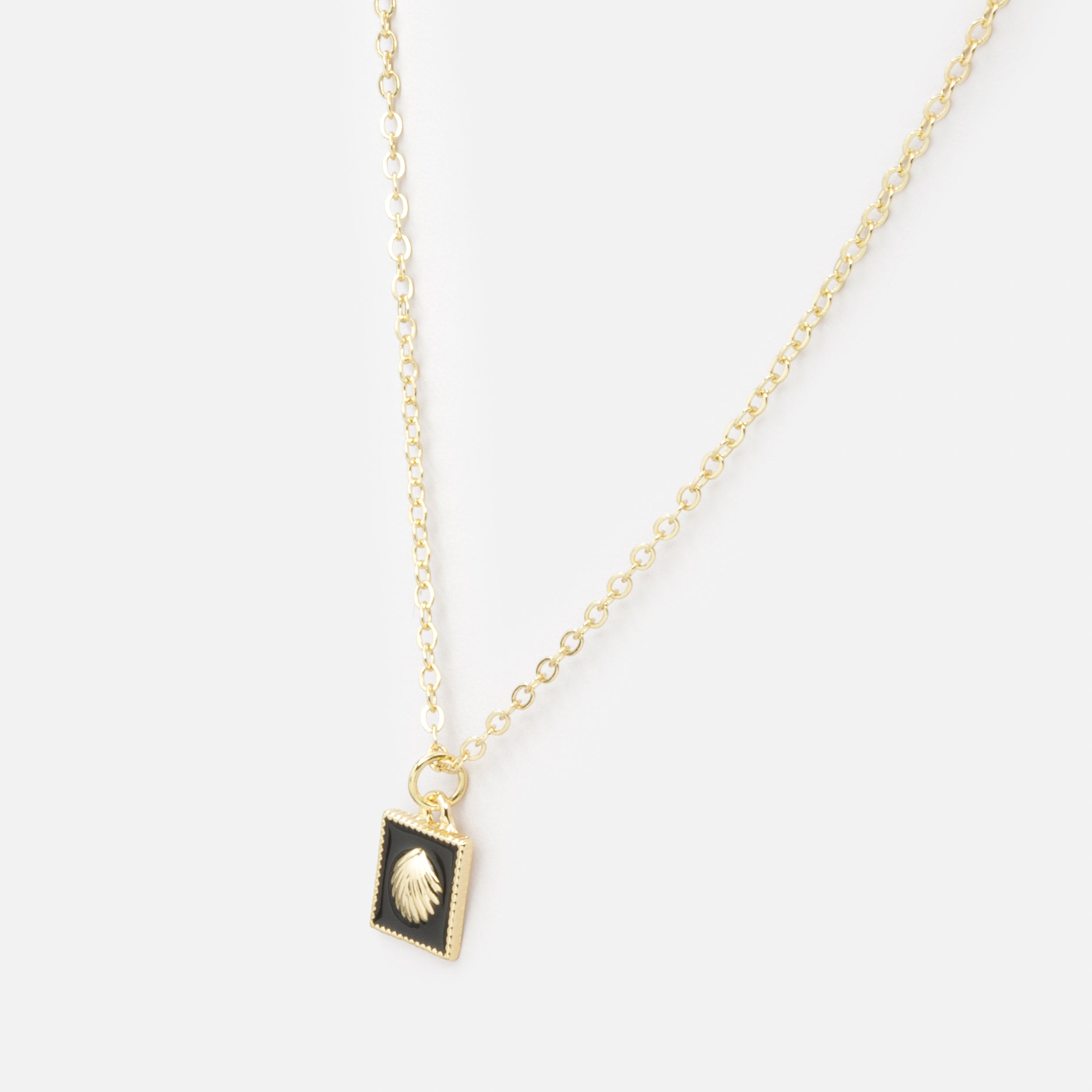 Collier doré avec breloque carrée coquillage sur fond noir