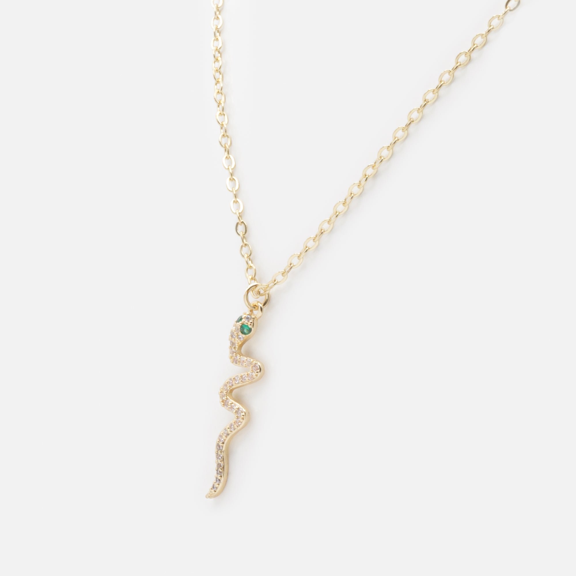 Gold snake charm necklace with cubic zirconia and emerald stones