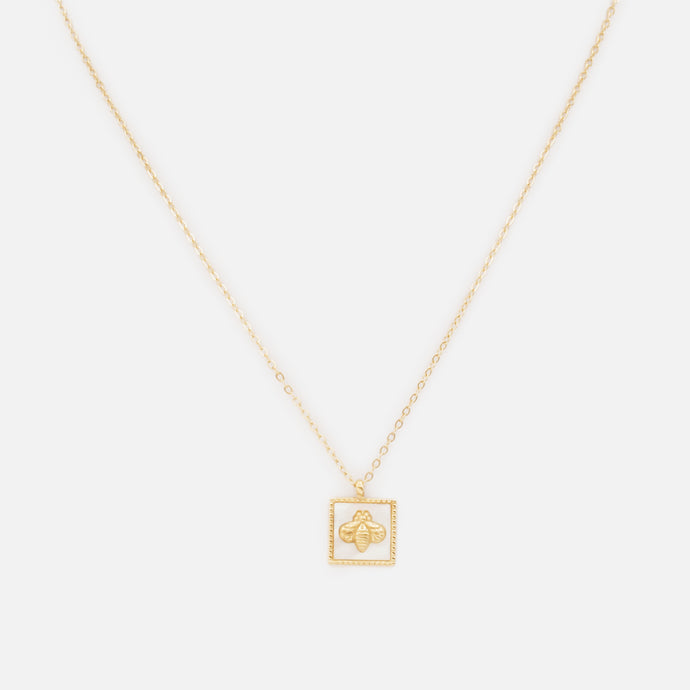 Golden stainless steel necklace with square bee charm on pearly white background