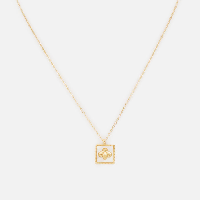 Golden stainless steel necklace with square bee charm on pearly white background
