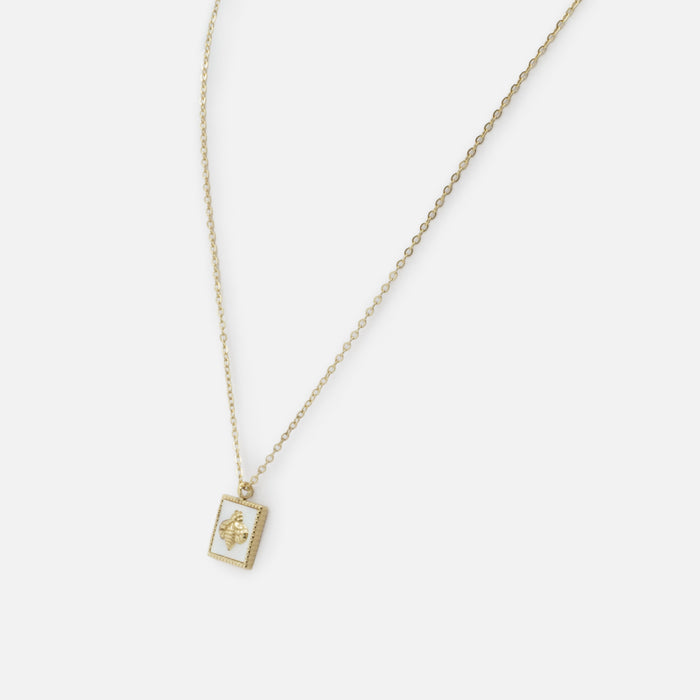 Golden stainless steel necklace with square bee charm on pearly white background