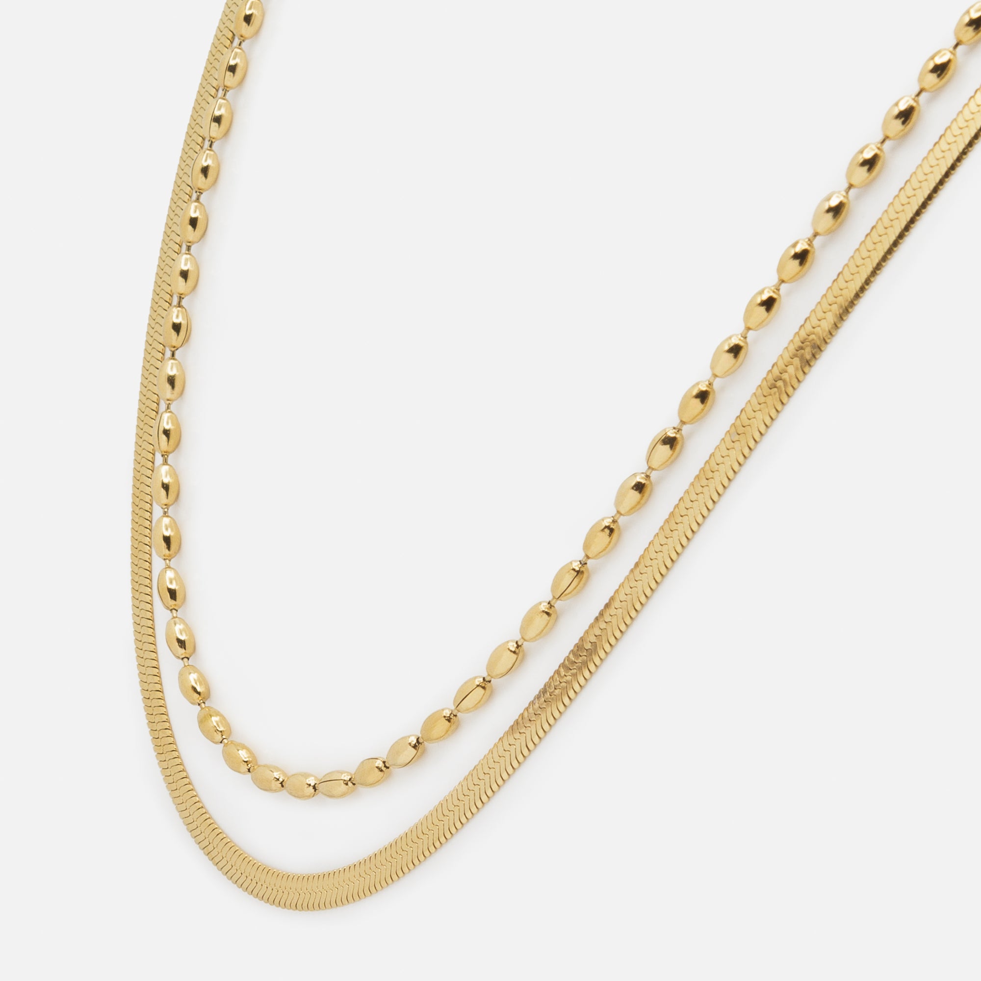 Gold double chain necklace with flat serpentine links and elongated stainless steel beads