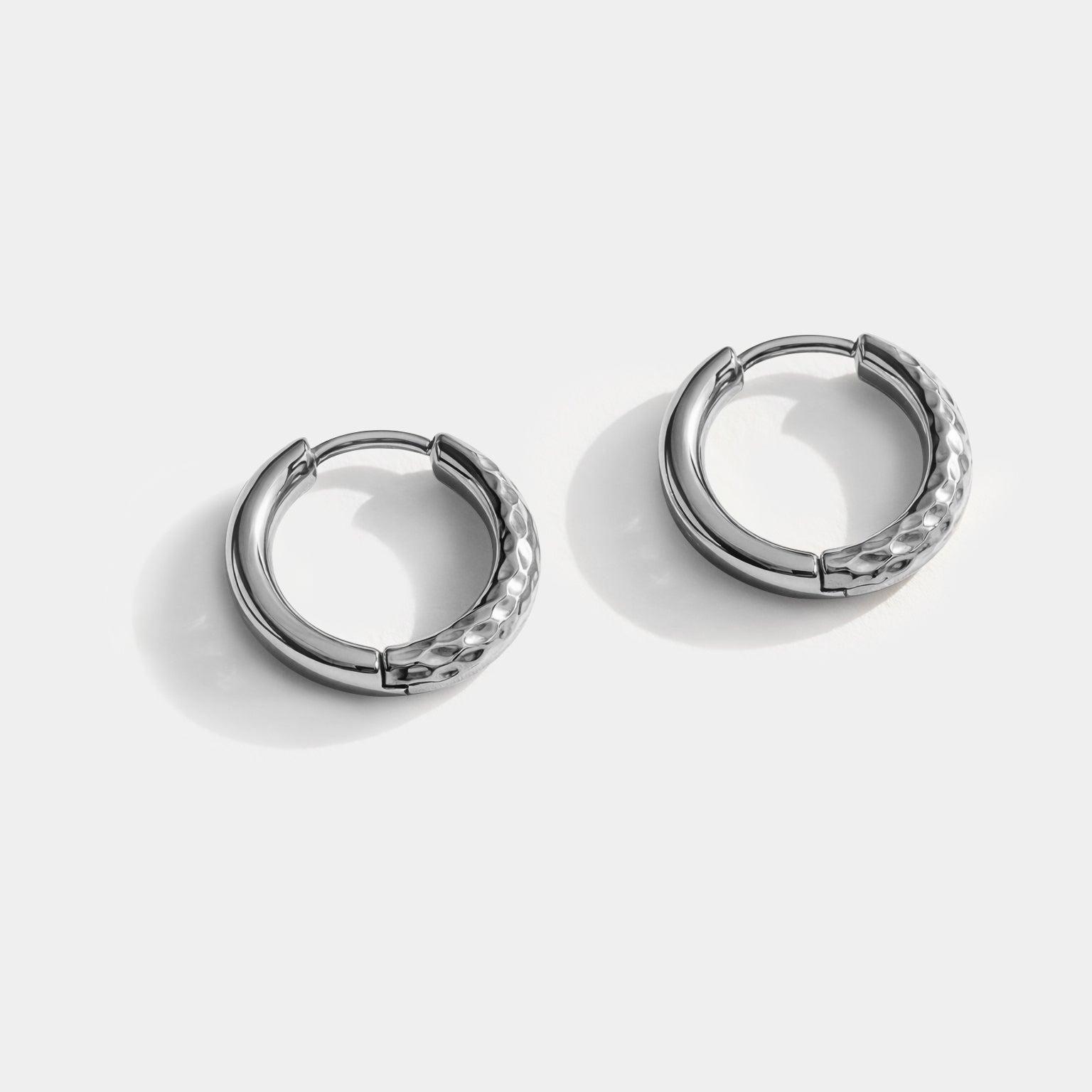 Bizou SS251E019SL – Silver stainless steel huggie hoop earrings with hammered honeycomb texture, high-polish inner band, angled view, Bizou jewelry