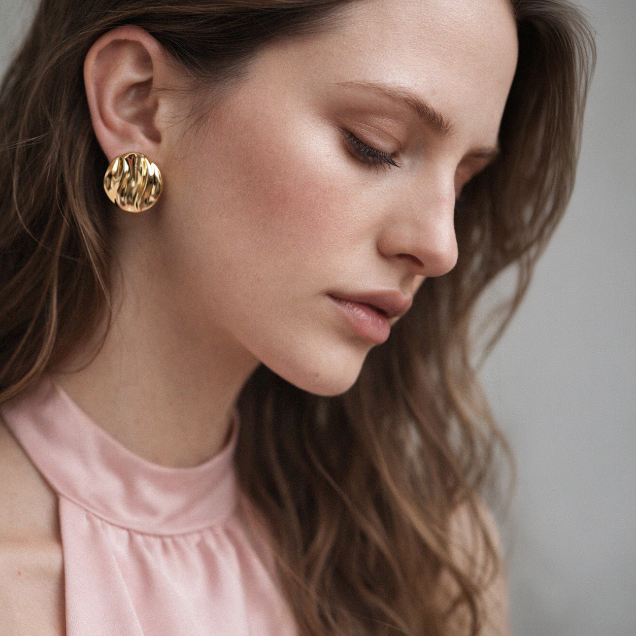 Bizou SF253E010GL – Woman wearing gold stainless steel wavy dome stud earrings, bold sculptural statement earring, side profile, Bizou jewelry

