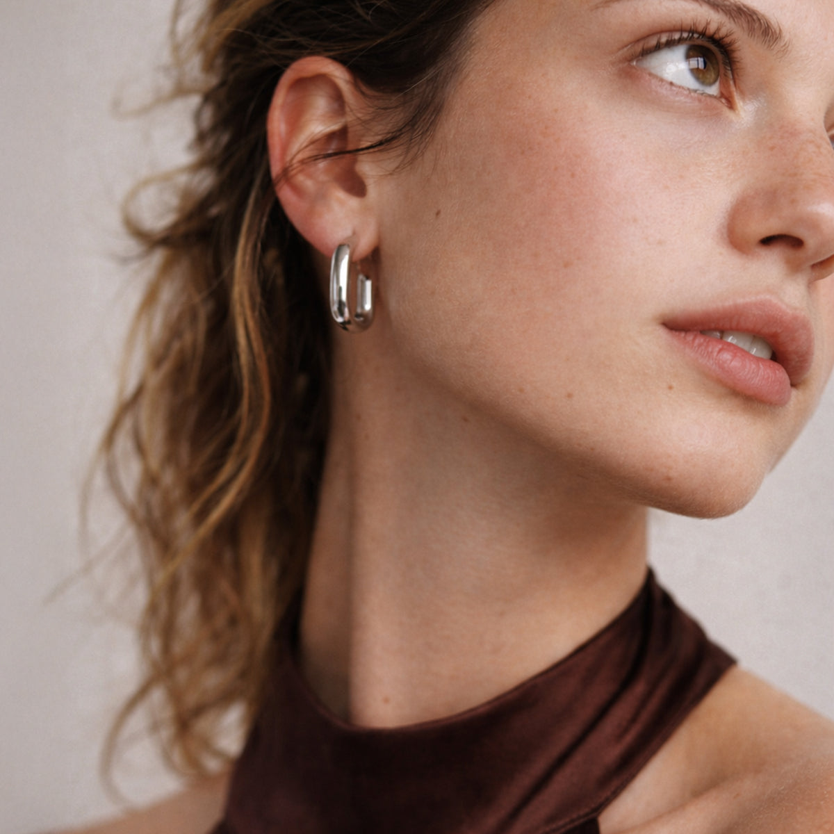 Bizou SF253E015SL – Woman wearing silver chunky rectangular stainless steel hoop earrings, side profile close-up, Bizou jewelry