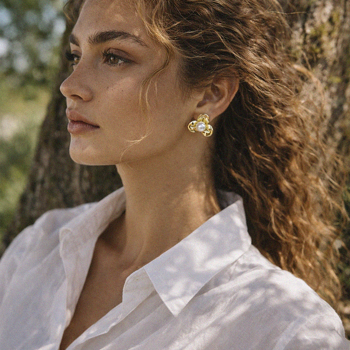 Bizou SS253E002GL – Woman wearing gold three-petal flower stud earrings with pearl, side profile, Bizou jewelry