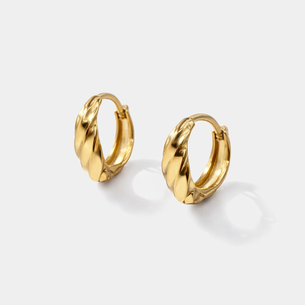 Bizou SS253E009GL – Gold wavy huggie hoop earrings in stainless steel, twisted sculptural band with hinged closure, angled view
