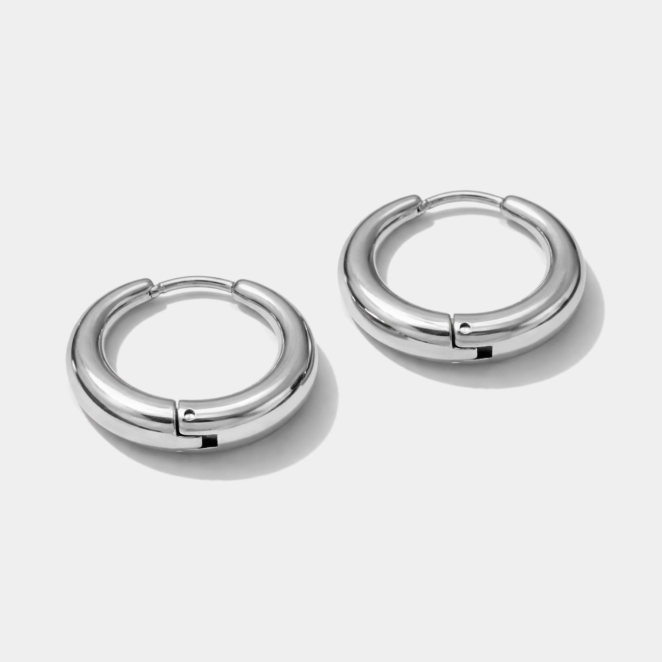 Bizou SS253E010SL – Silver stainless steel Essence huggie hoop earrings, smooth high-polish tube band, angled view, Bizou jewelry

