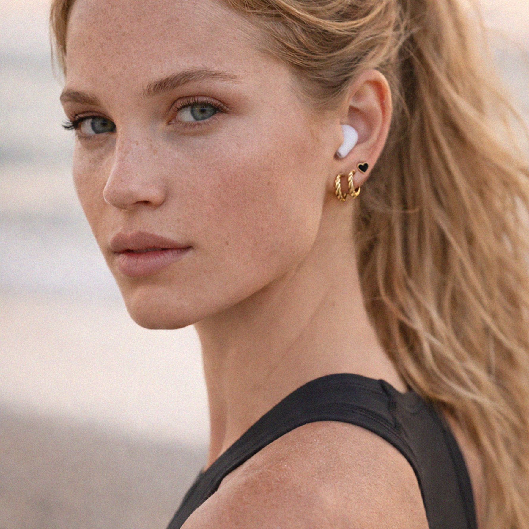 Bizou SS253E013GL – Woman wearing gold black enamel heart stud earring from stainless steel trio set, stacked ear look, side profile, Bizou jewelry


