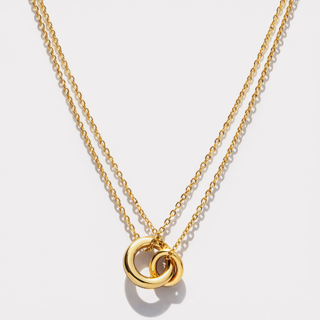 Bizou SS253N017GL – Gold interlinked rings double chain necklace in stainless steel, two tubular ring pendants on layered cable chains, front view
