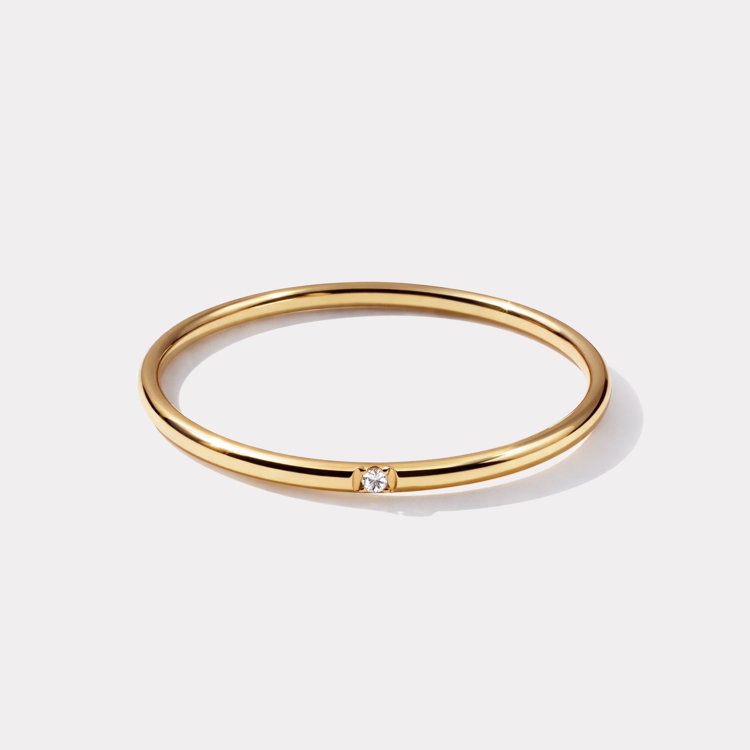 Bizou SS253R024GL – Gold thin band solitaire CZ ring in stainless steel, delicate round band with single flush-set cubic zirconia, angled view

