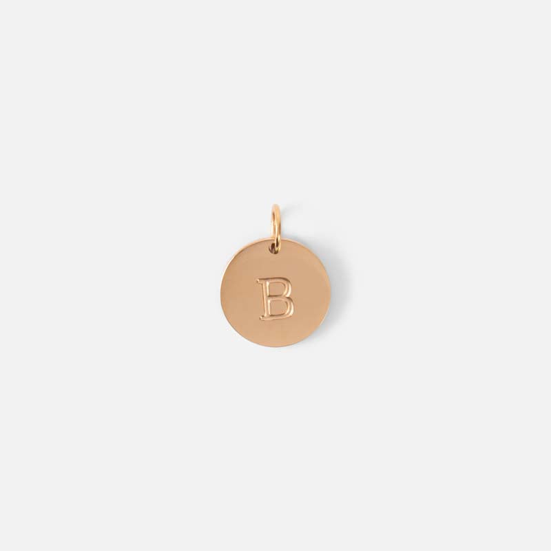 Small symbolic golden charm engraved with the letter of the alphabet "b"