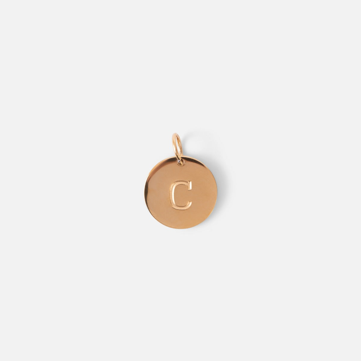 Small symbolic golden charm engraved with the letter of the alphabet "c"