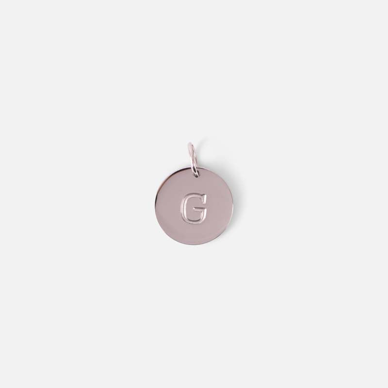 Small symbolic silvered charm engraved with the letter of the alphabet "g"