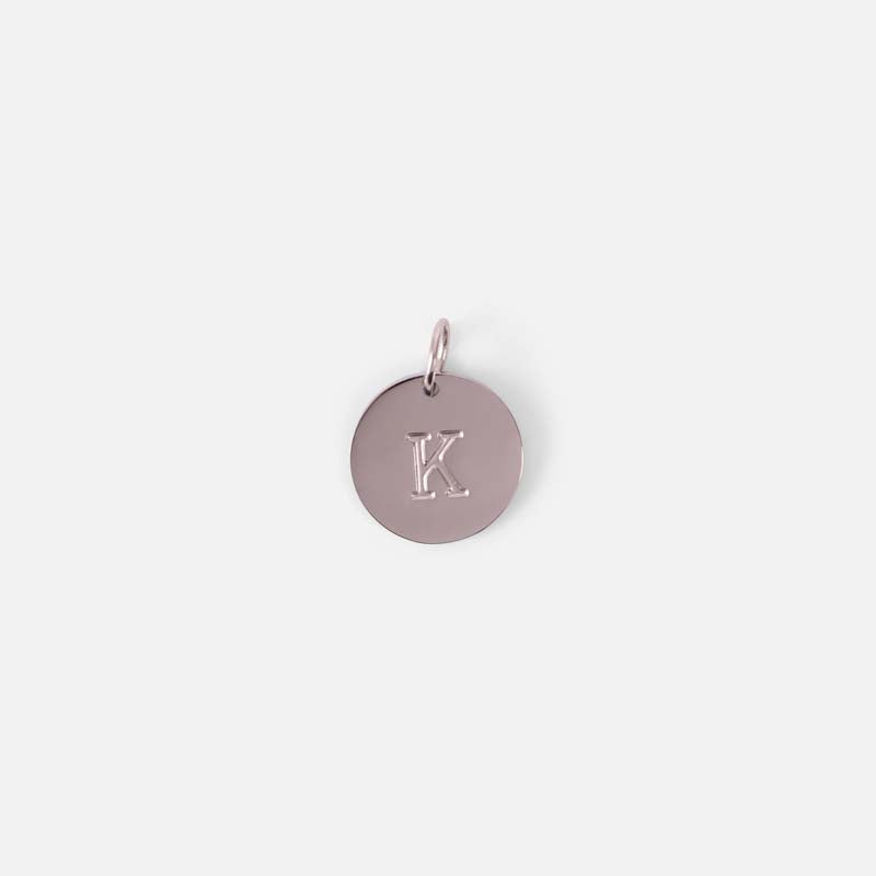 Small symbolic silvered charm engraved with the letter of the alphabet "k"