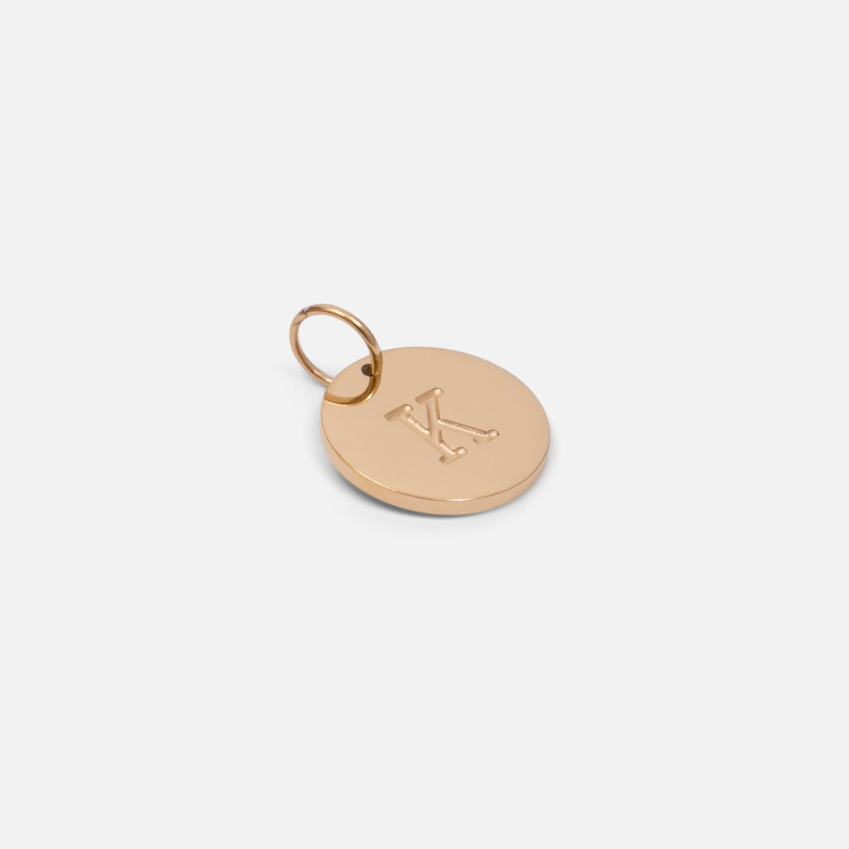 Small symbolic golden charm engraved with the letter of the alphabet "k"
