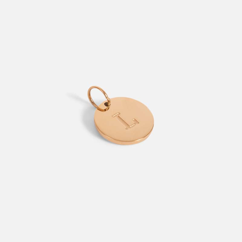 Small symbolic golden charm engraved with the letter of the alphabet "l"