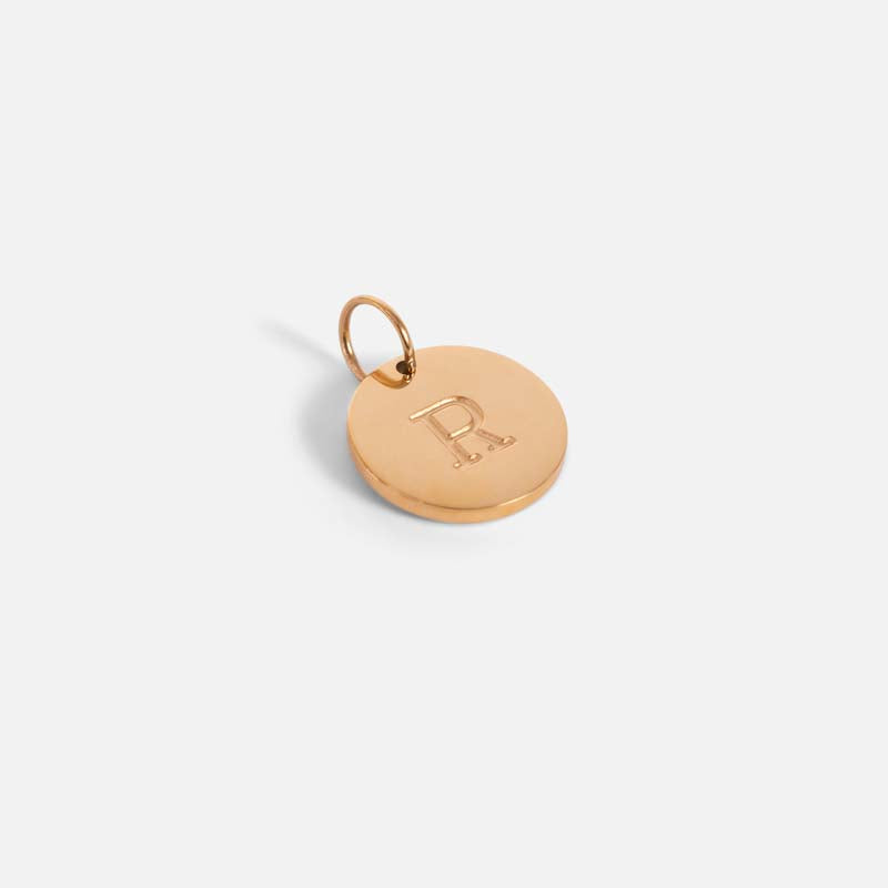 Small symbolic golden charm engraved with the letter of the alphabet 