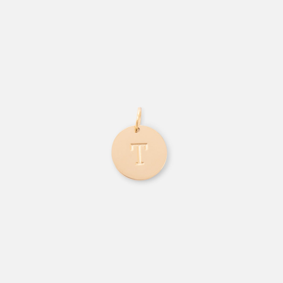 Small symbolic golden charm engraved with the letter of the alphabet "t"