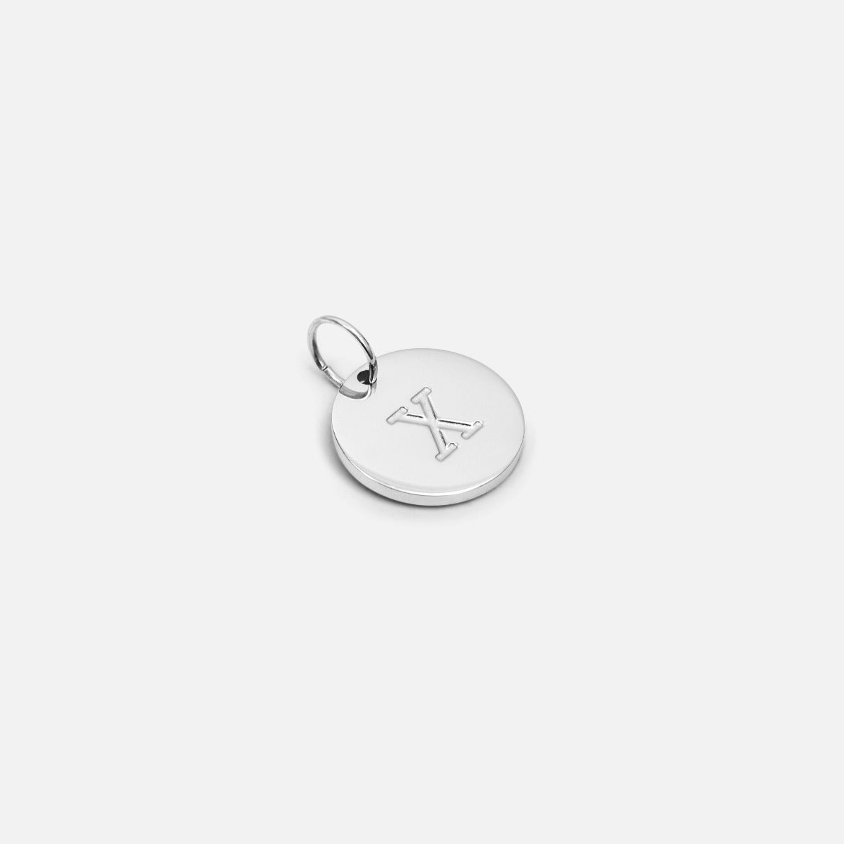 Small symbolic silvered charm engraved with the letter of the alphabet "x"