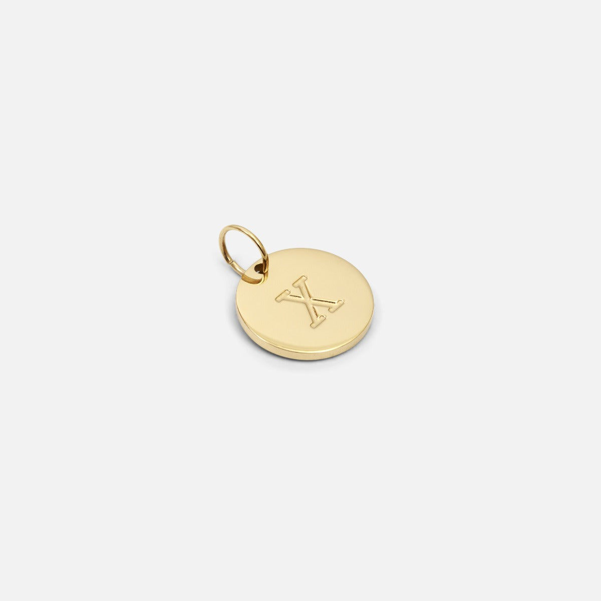 Small symbolic golden charm engraved with the letter of the alphabet "x"