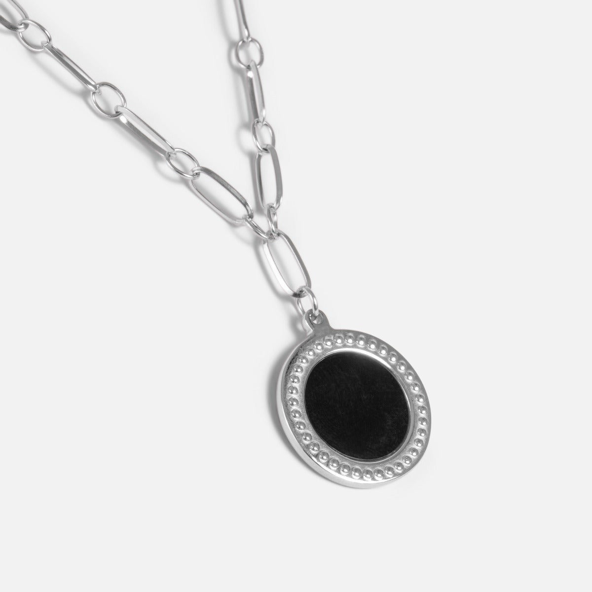 Long silver stainless steel necklace with large links and black round charm and textured outline