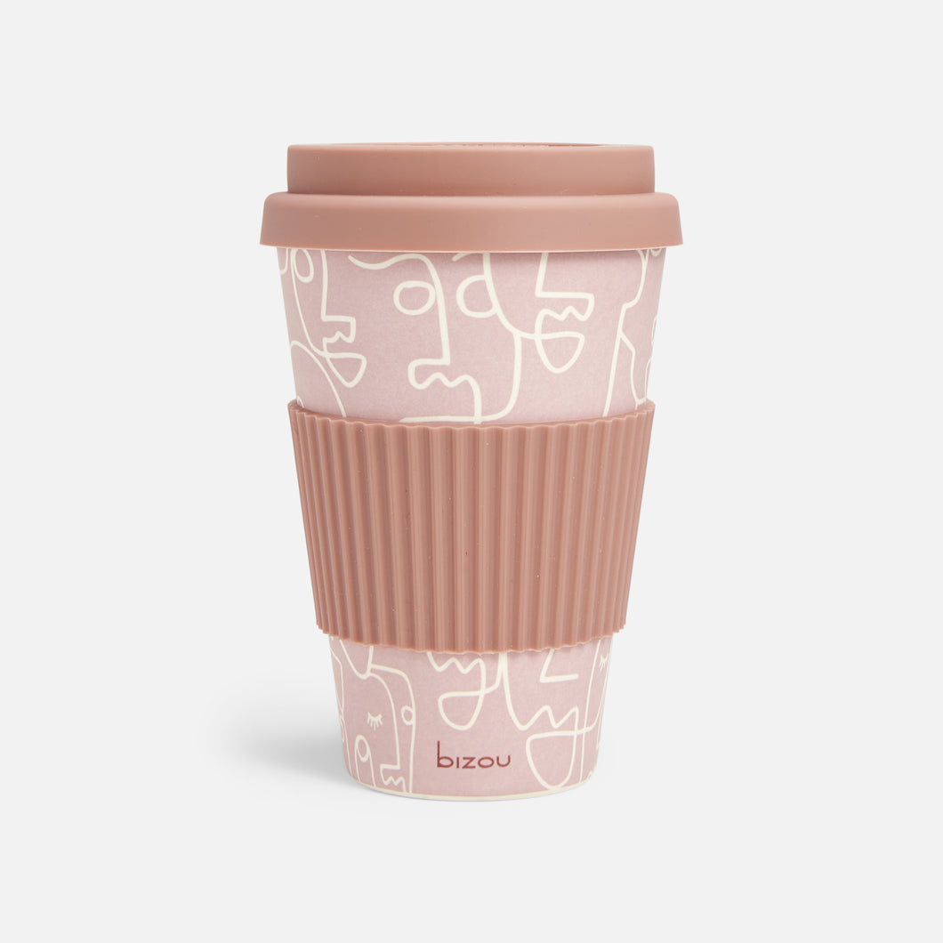Reusable pink bamboo coffee mug with abstract faces